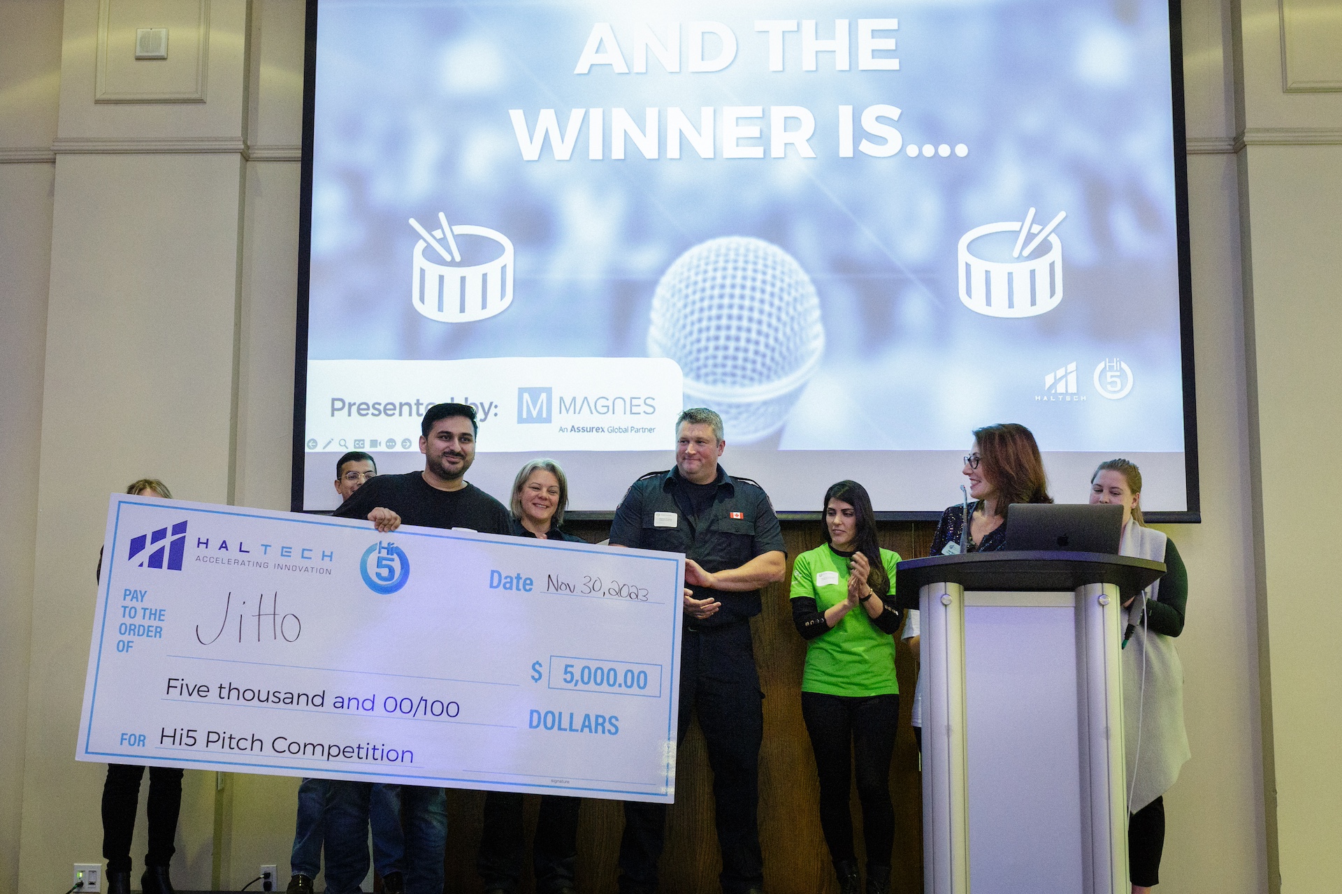 Hi5 Pitch Competition finalists on stage as Mani holds winning cheque